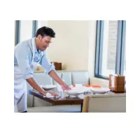 A restaurant worker is wearing an apron and clearing the dishes after customers have left.