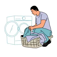 A woman is kneeling while loading clothes into a washing machine.