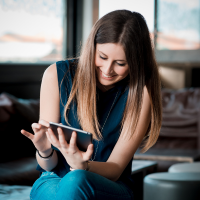 A smiling young woman using a tablet, reading an e-book and learning English