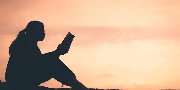 An ESL student reading a vocabulary lesson at sunset