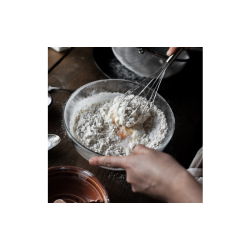 A woman mixing eggs and flour to make a cake.