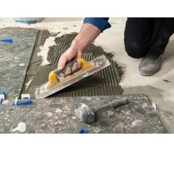 A man using a notched trowel