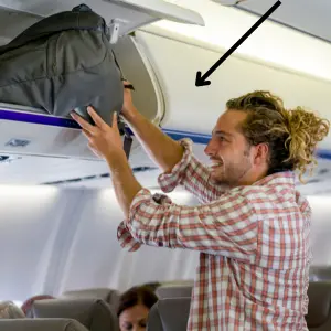 Plane's overhead compartman A man putting his luggage in an overhead compartment