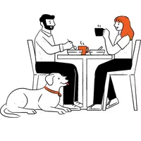 A couple eating at a restaurant with their dog