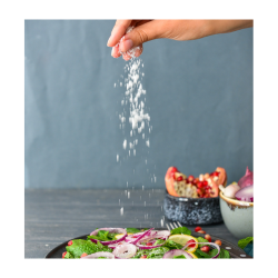 A woman sprinkling salt into a salad