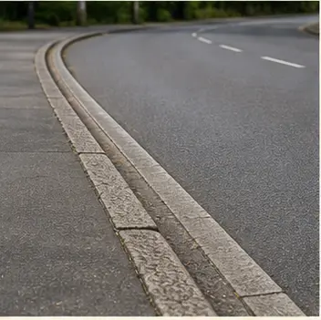 A realistic vocabulary image showing a kerb at the edge of a road.